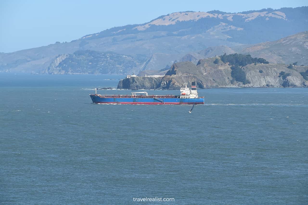 Large cargo ship and yacht in the Golden Gate from Lincoln Park in San Francisco, California, US