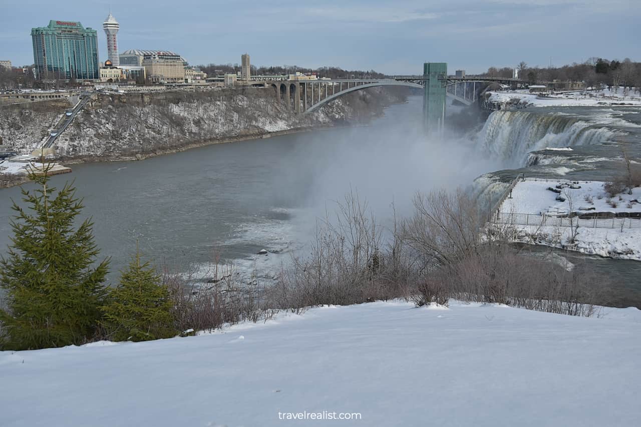 Winter views of American Falls, Observation Tower, and Rainbow Bridge from Niagara Falls State Park, New York, US