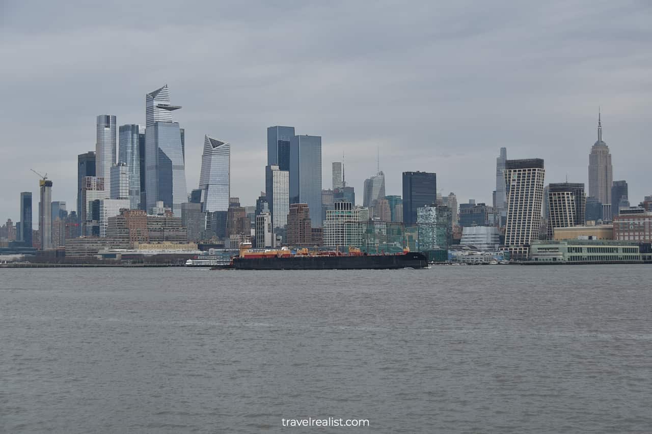 Barge on Hudson River passes The Edge and Empire State Building in New York City, New York, US