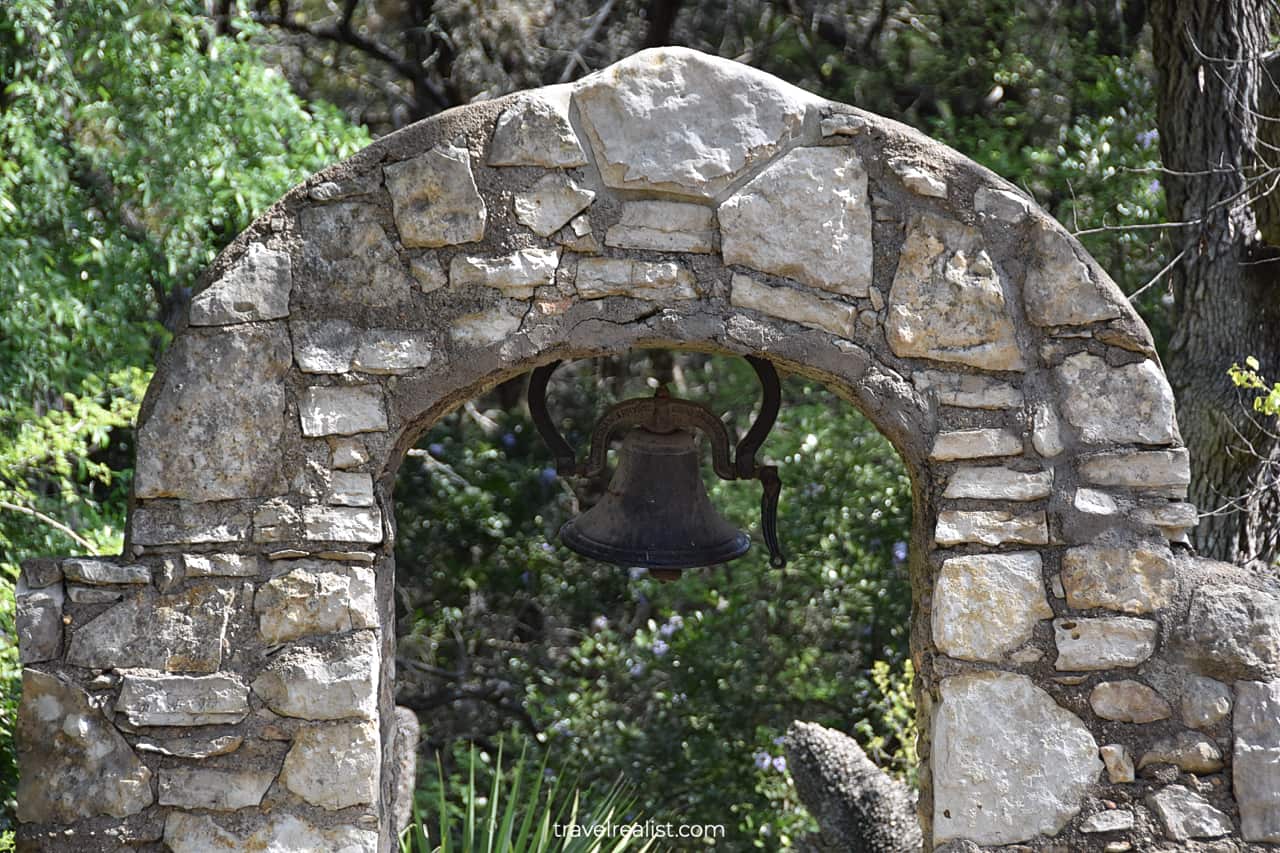 Stone arch with iron bell in Mayfield Park and Nature Preserve in Austin, Texas, US